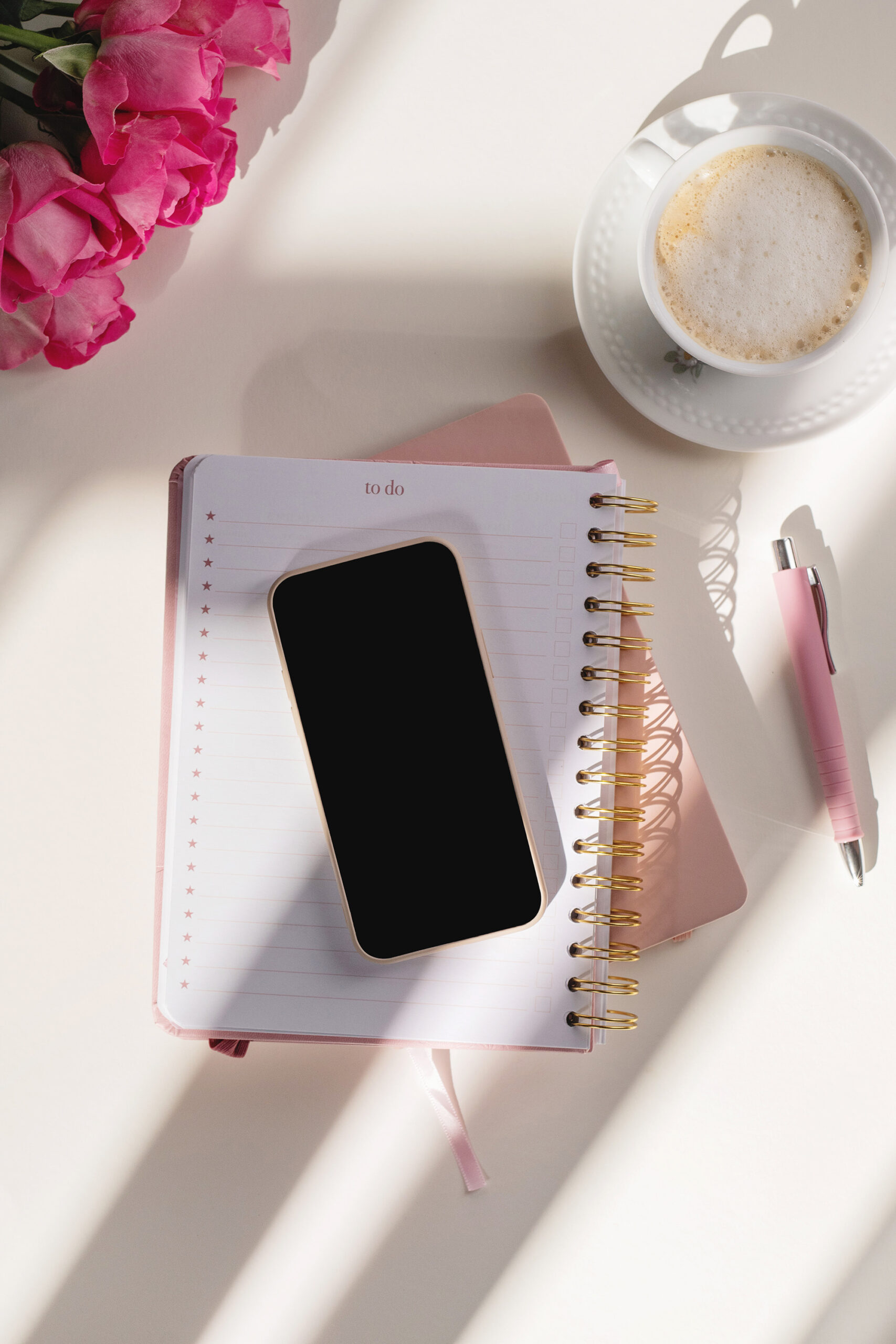Pink planner, coffee, flowers, and phone representing a single mom planning, healing, and building a rich life through faith, wealth, and wellness.